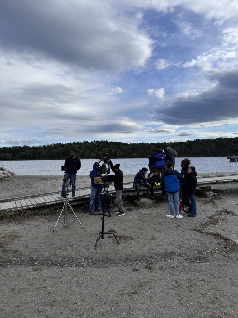 International film crew and camera setup on a lakeshore in Norway during the Butta Bond production
