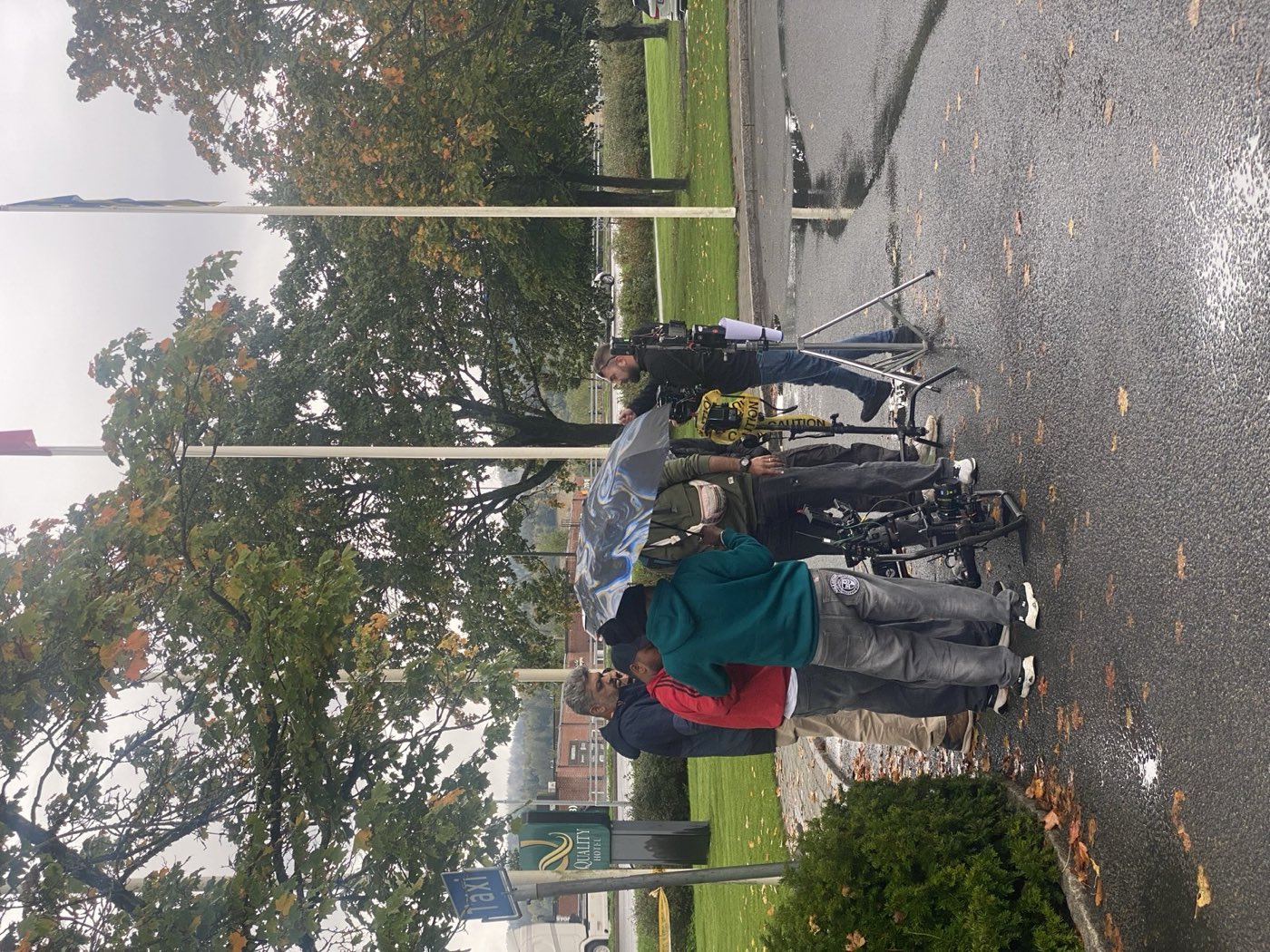 Film crew shooting in rain in Norway with camera protected under an umbrella